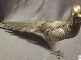 a metal bird that is sitting on a cloth
