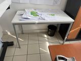 une table blanche sur laquelle sont posés des papiers, dans une petite pièce