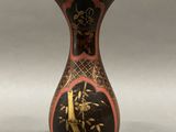 a black and red vase with gold designs on it