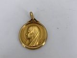a gold medal with a woman ' s face on it