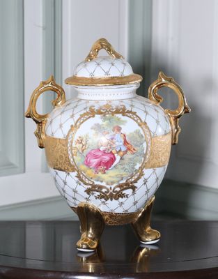 un vase blanc orné d'un motif doré, posé sur une table