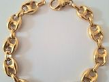 a close up of a gold chain bracelet on a white surface