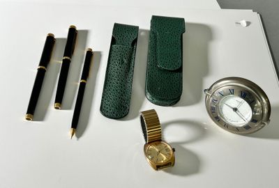 a watch, pen, watch case, watch and other items on a table