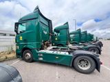 many green semi trucks parked in a parking lot