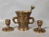 three brass vases and a candle holder on a table