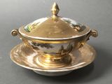 a gold and white bowl and saucer on a saucer