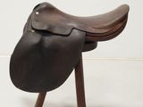 an image of a saddle on a wooden stand against a white wall