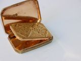a small gold box with a sandwich inside of it
