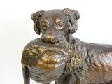 a bronze statue of a dog holding a ball in its mouth