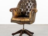 une chaise de bureau en cuir marron, équipée de roulettes et dotée d'un piètement en bois