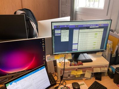un bureau sur lequel sont posés deux écrans et un ordinateur portable