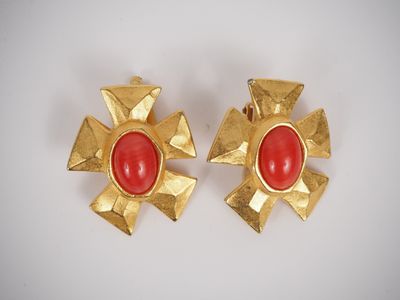 a pair of gold and red earrings on a white surface