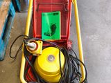 un chariot rouge et jaune muni d'un tuyau jaune et d'un panneau vert