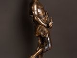 a bronze statue of a man holding a bag on a wooden table