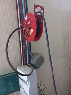 une lance à incendie rouge raccordée à un chauffe-eau dans un garage