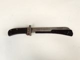 an old knife with a black handle on a white surface