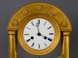 a gold clock that is sitting on a stand