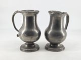 two silver vases sitting next to each other on a table