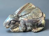 un lapin en argent posé sur un récipient en verre