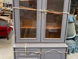 a gray cabinet with glass doors and a rope on the top