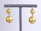a pair of gold ball earrings on a stand