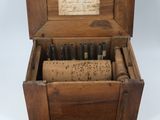 une vieille boîte en bois sur laquelle il y a une inscription et qui contient un tas de vis