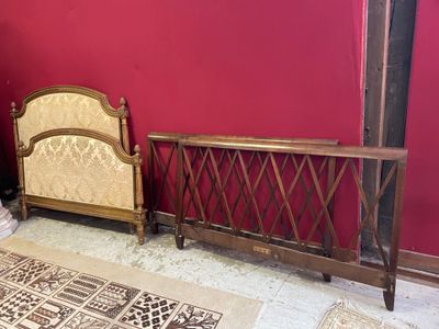 un lit avec une tête et un pied de lit en bois, adossé à un mur rouge