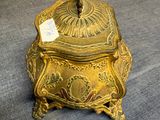 an antique brass box with a lid on a blue surface