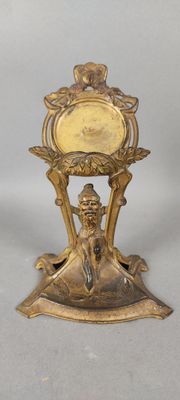 une horloge en or posée sur un socle, sur laquelle est assise une femme