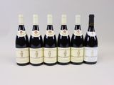 six bouteilles de vin alignées sur une surface blanche