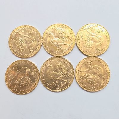 six pièces d'or de formes et de tailles différentes sur une surface blanche