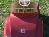 a red toy car sitting in the grass on the ground