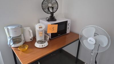 une petite table sur laquelle se trouvent un ventilateur et un micro-ondes