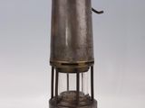 an old fashioned metal lantern with a glass top on a white surface