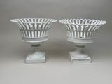 pair of white vases sitting on top of a white pedestal