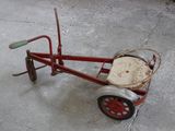 un petit tricycle rouge avec un panier à l'arrière