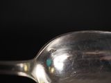 a silver spoon with a tiny blue dot on it