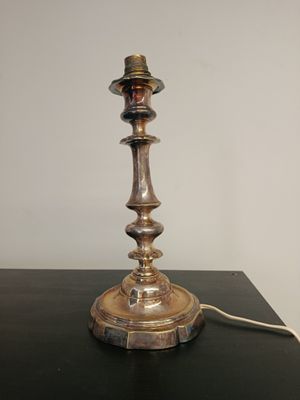 une lampe posée sur une table, sur laquelle est posé un chapeau