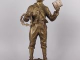 bronze figurine of a boy holding a book and a book