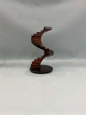 une image représentant une sculpture d'un escalier en colimaçon posée sur un socle en bois