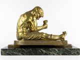 bronze statue of a man sitting on a marble base reading a book