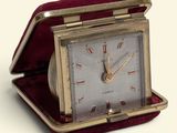 a small clock that is sitting in a red case