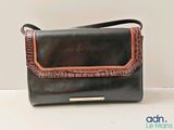 black and brown handbag with brown trim on a white surface