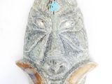 a stone mask hanging on a wall on a white background