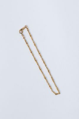 un collier en or avec une longue chaîne sur fond blanc
