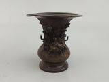 un vase en bronze posé sur une surface blanche