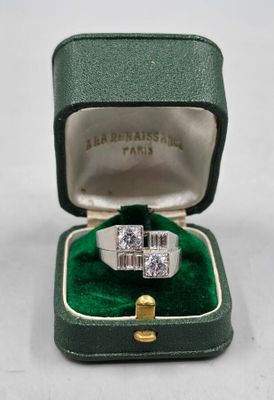 une photo d'une bague en diamant dans un écrin vert posé sur une surface blanche