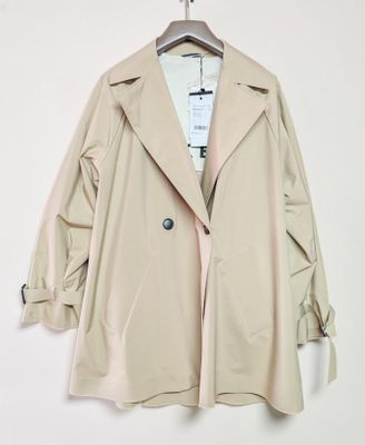 beige trench coat hanging on a hanger against a white wall