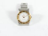 une montre-bracelet argentée et dorée posée sur une surface blanche