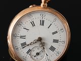 a gold pocket watch with roman numerals on it
